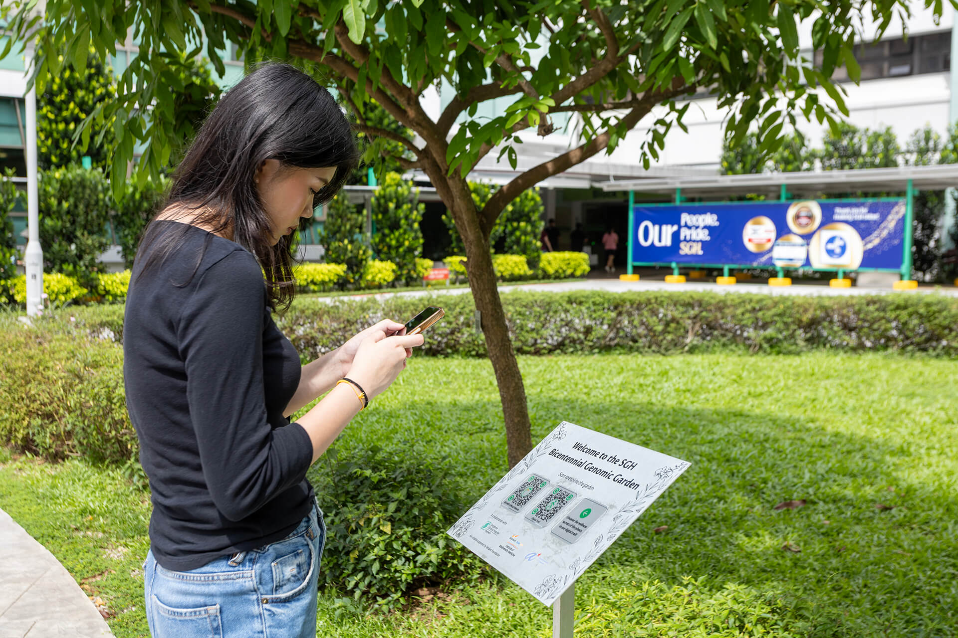 A visitor scanning the QR code at the SGH Bicentennial Genomic Garden trailhead.